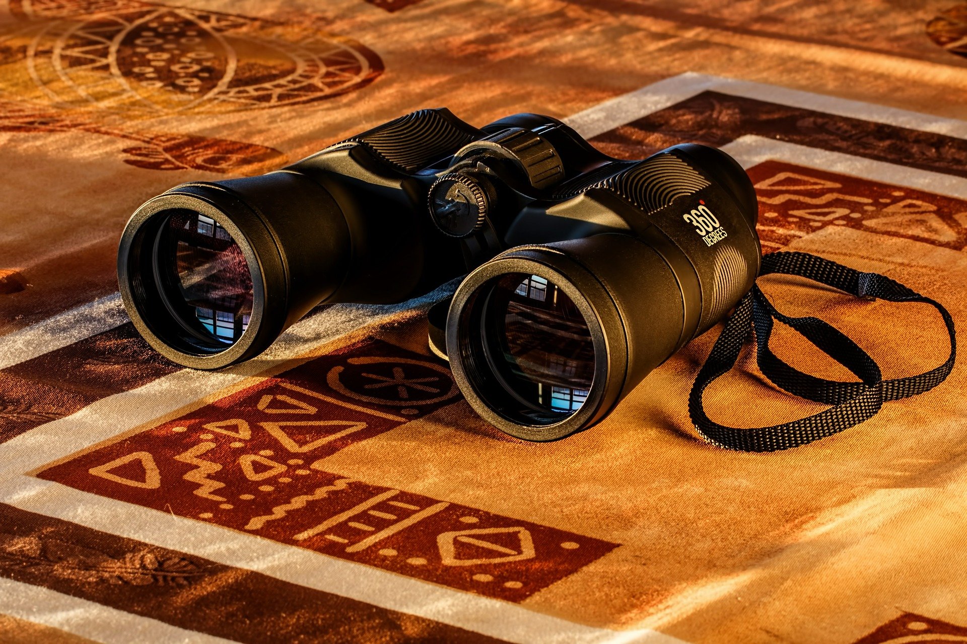 binoculars with a black strap placed on a mat